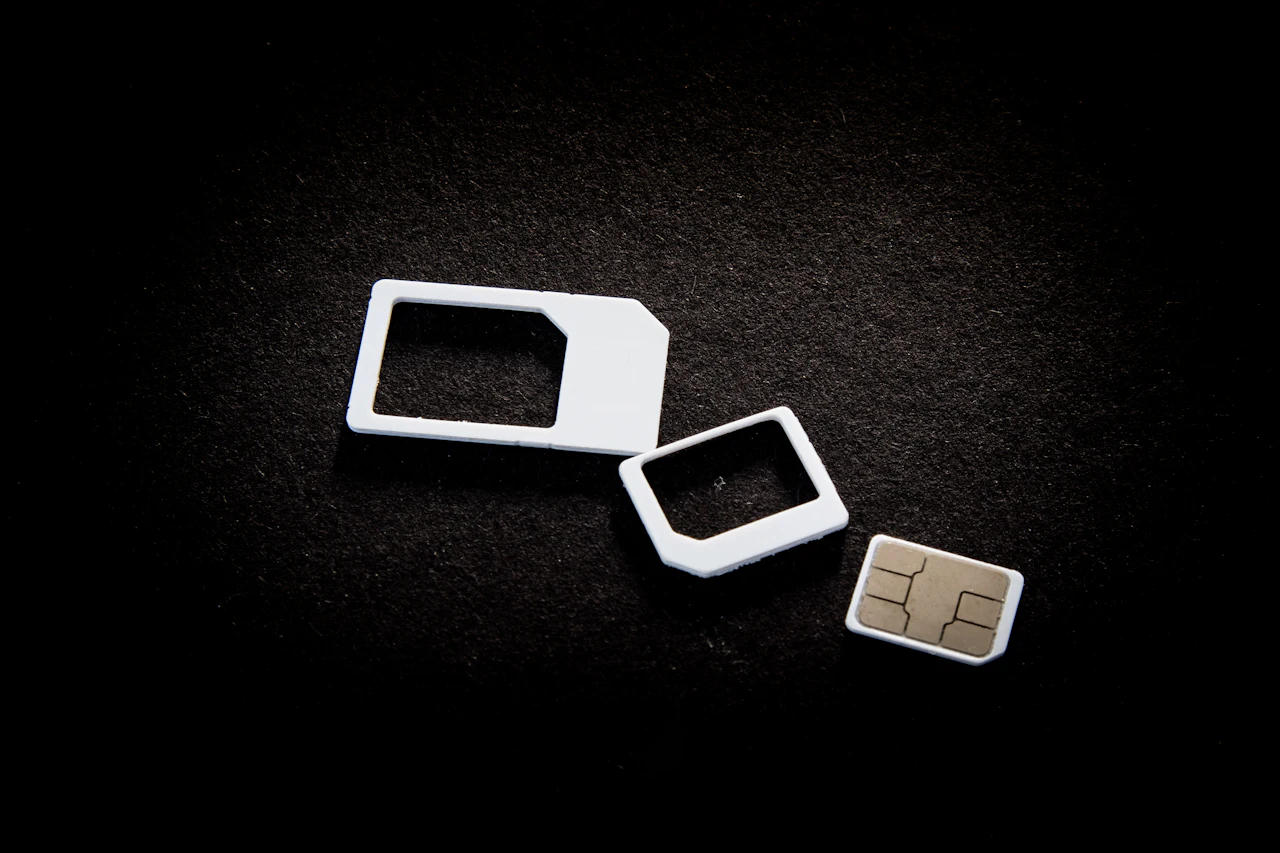 A SIM card and its adaptors on a dark surface